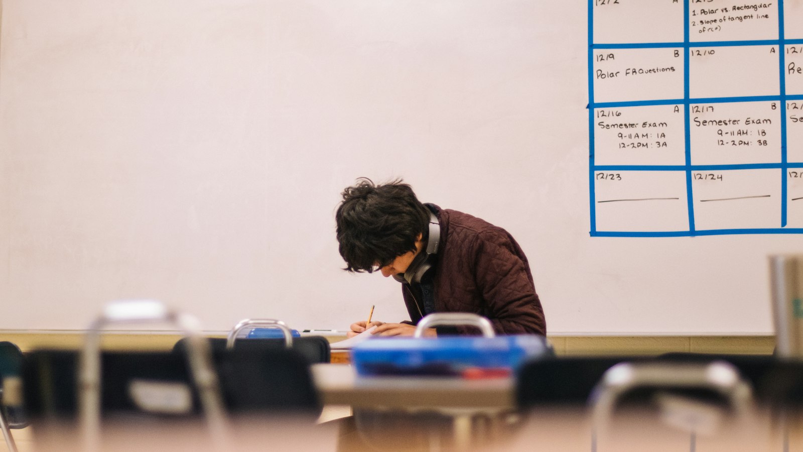 Student writing at a desk in a high school classroom